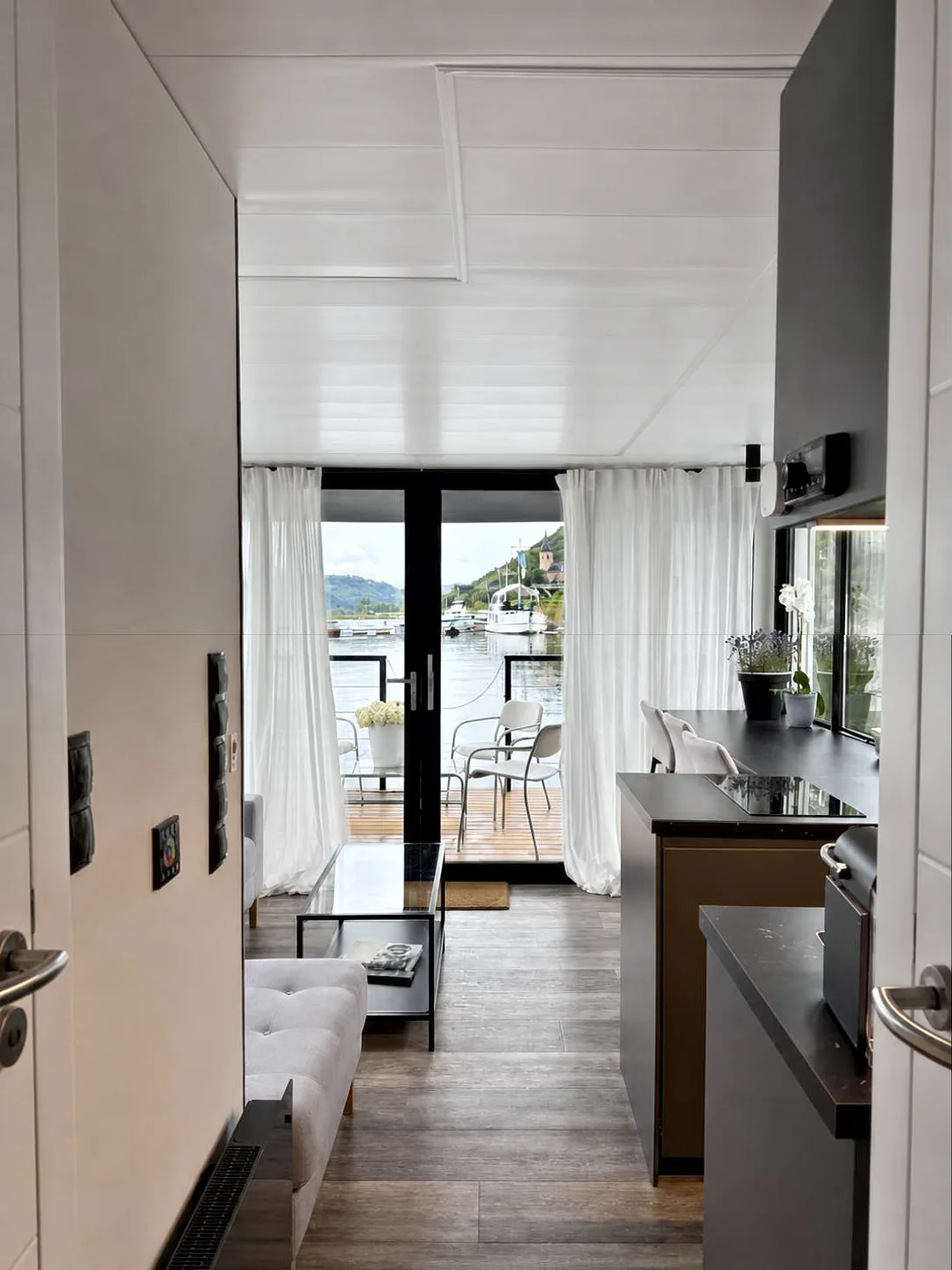 Blick vom Eingang von Modern 1 durch den Wohnraum auf die Terrasse und den Fluss.