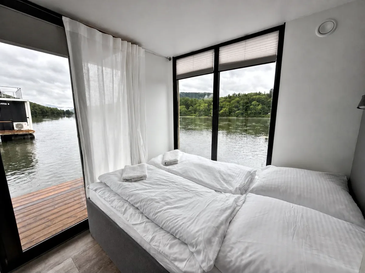 Schlafzimmer von Modern 1 mit Doppelbett vor bodentiefen Fenstern zum Rhein.