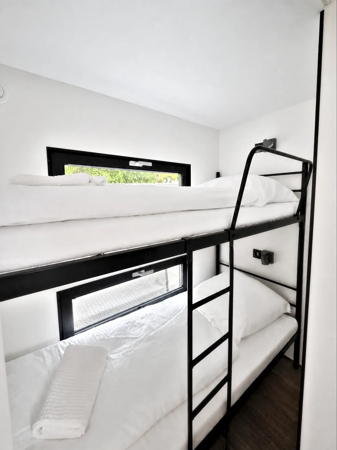 Zweites Schlafzimmer von Modern 1 mit schwarzem Stockbett, weißer Bettwäsche und Fensterband.