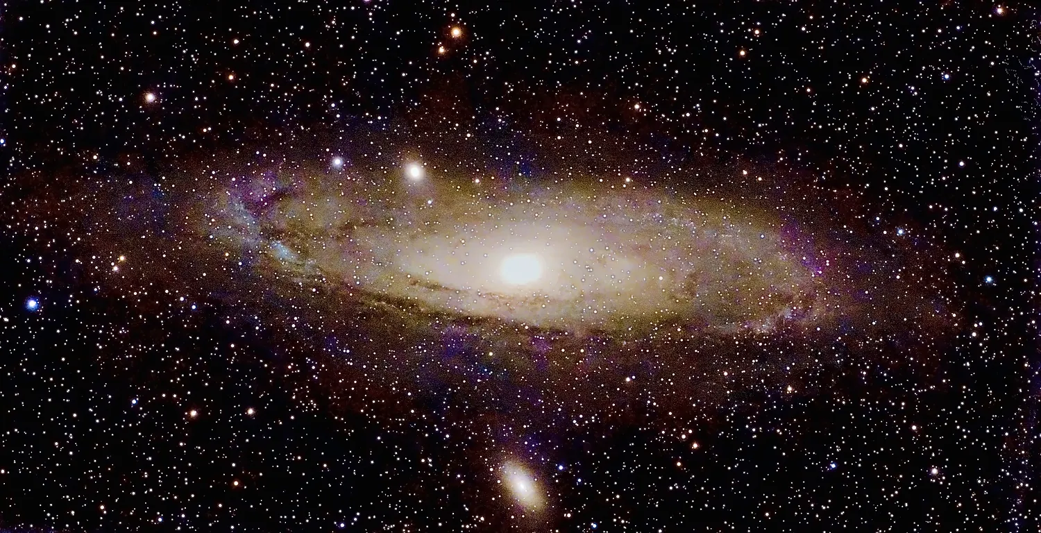 Die Andromedagalaxie M 31 als schräg stehende Spirale mit Staubbändern, daneben die Begleitgalaxien M 32 und M 110.