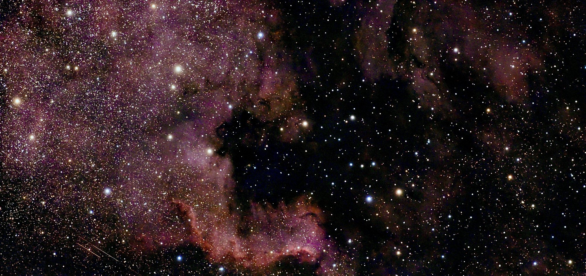 Der Nordamerikanebel NGC 7000: rot leuchtender Wasserstoff, davor eine dunkle Staubbucht in Form des Golfs von Mexiko.