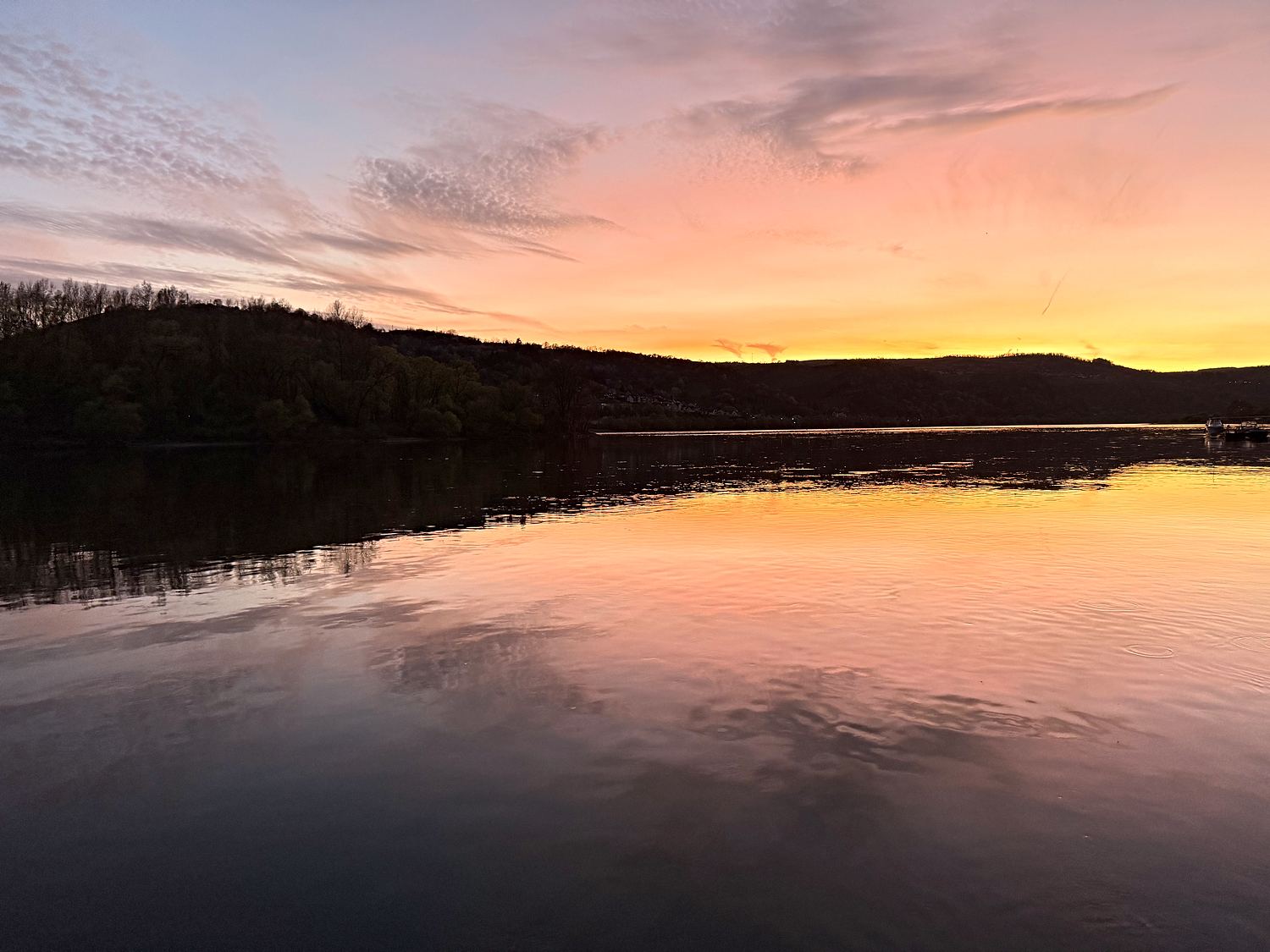 Orange-violetter Sonnenuntergang über dem Rhein, der Himmel spiegelt sich im stillen Wasser.