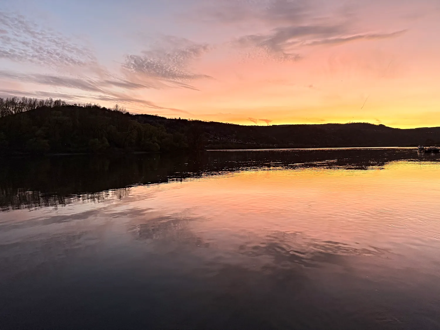 Orange-violetter Sonnenuntergang über dem Rhein, der Himmel spiegelt sich im stillen Wasser.