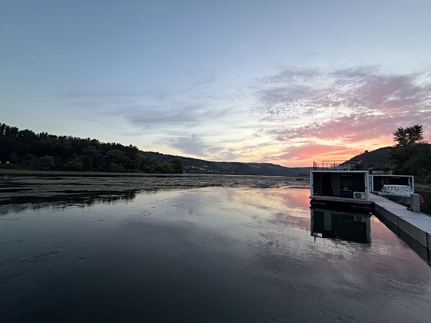 Abendrot über dem Rheinbogen, im Vordergrund die dunkle Silhouette des Stegs.