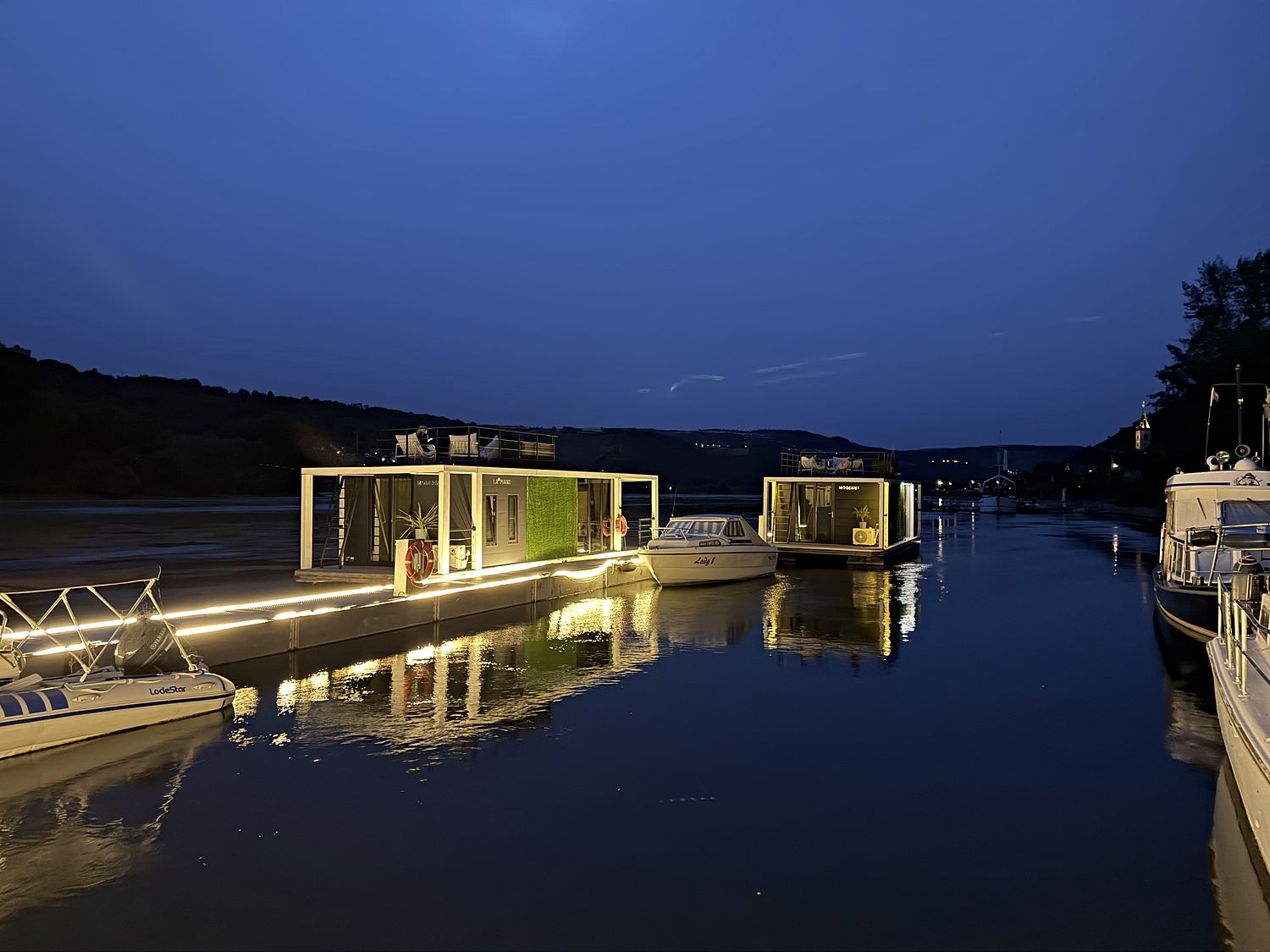 Die beleuchteten Hausboote in der blauen Stunde, gespiegelt im ruhigen Seitenarm.