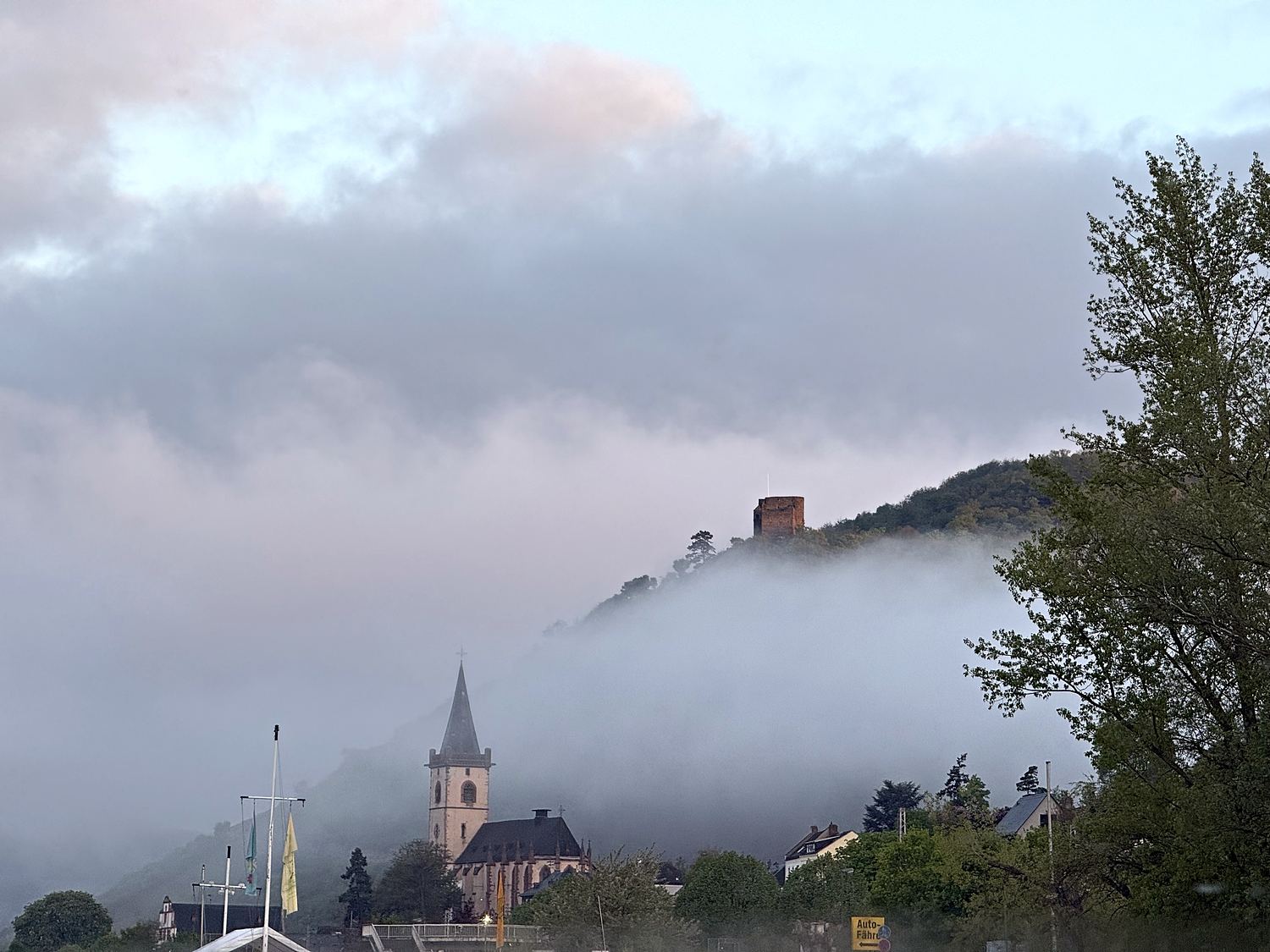 Morgennebel über Lorch: Kirchturm und Burg Nollig ragen aus der Nebeldecke.