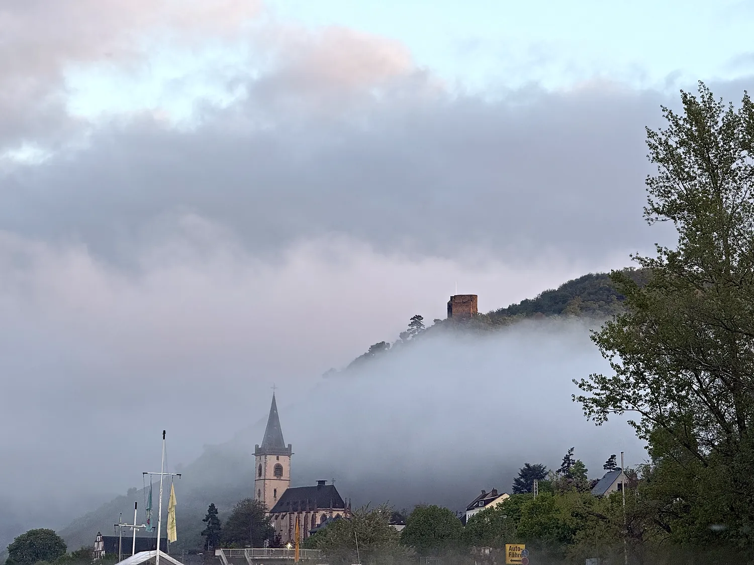 Morgennebel über Lorch: Kirchturm und Burg Nollig ragen aus der Nebeldecke.
