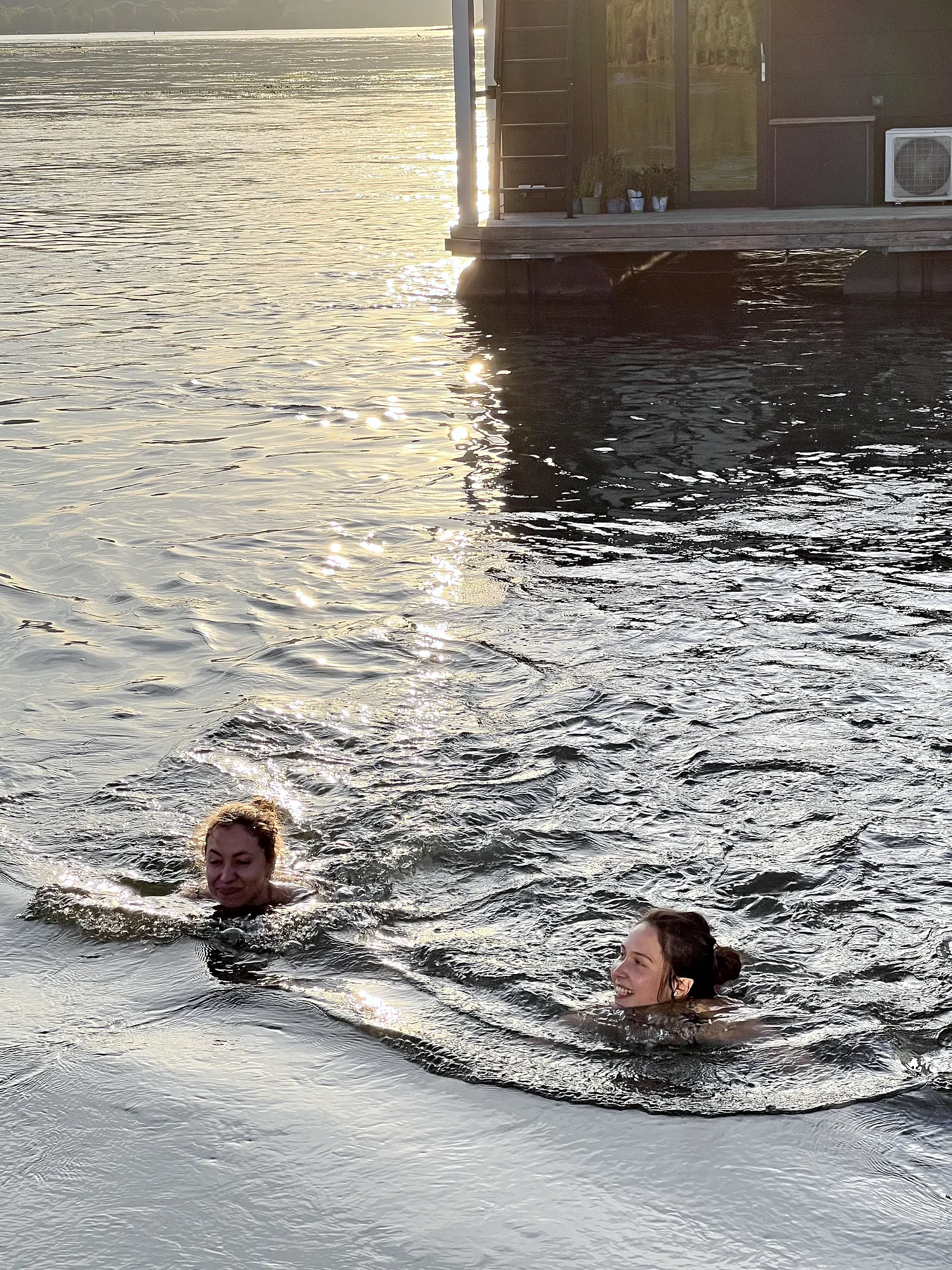 Blick auf den Rhein neben dem Hausboot; im Wasser zwei Schwimmer außerhalb der Marina.