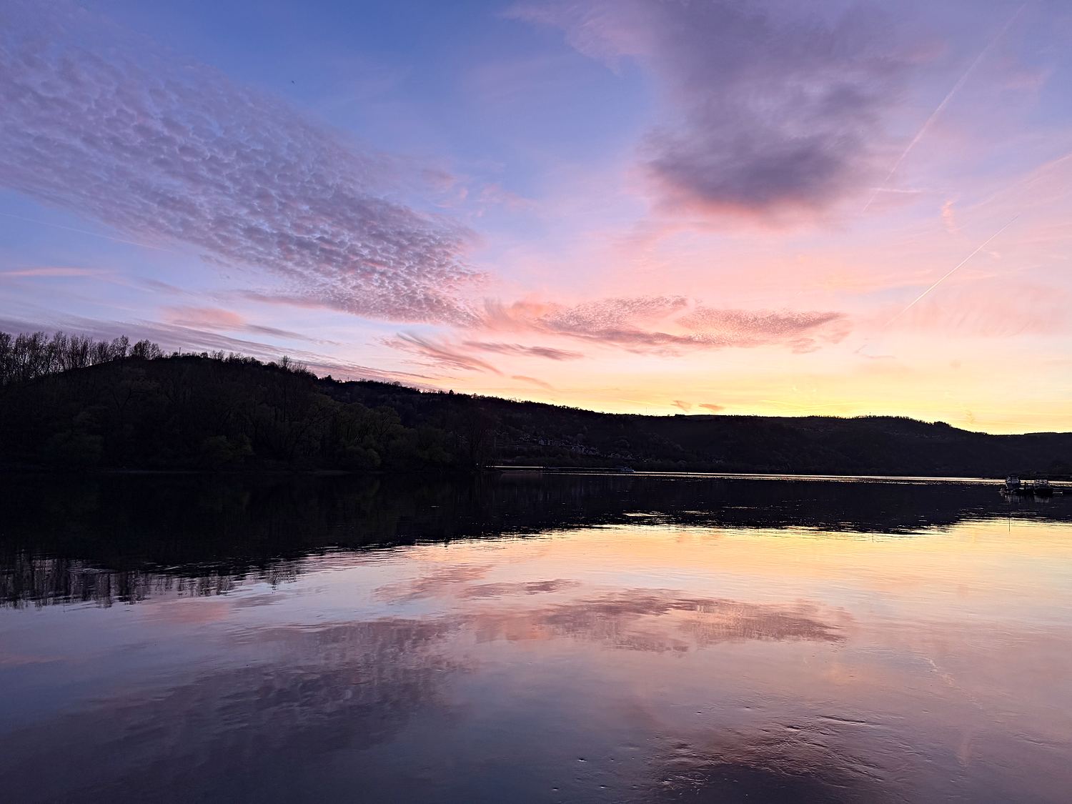Rosafarbene Abendwolken über dem Rhein, das Wasser liegt spiegelglatt.
